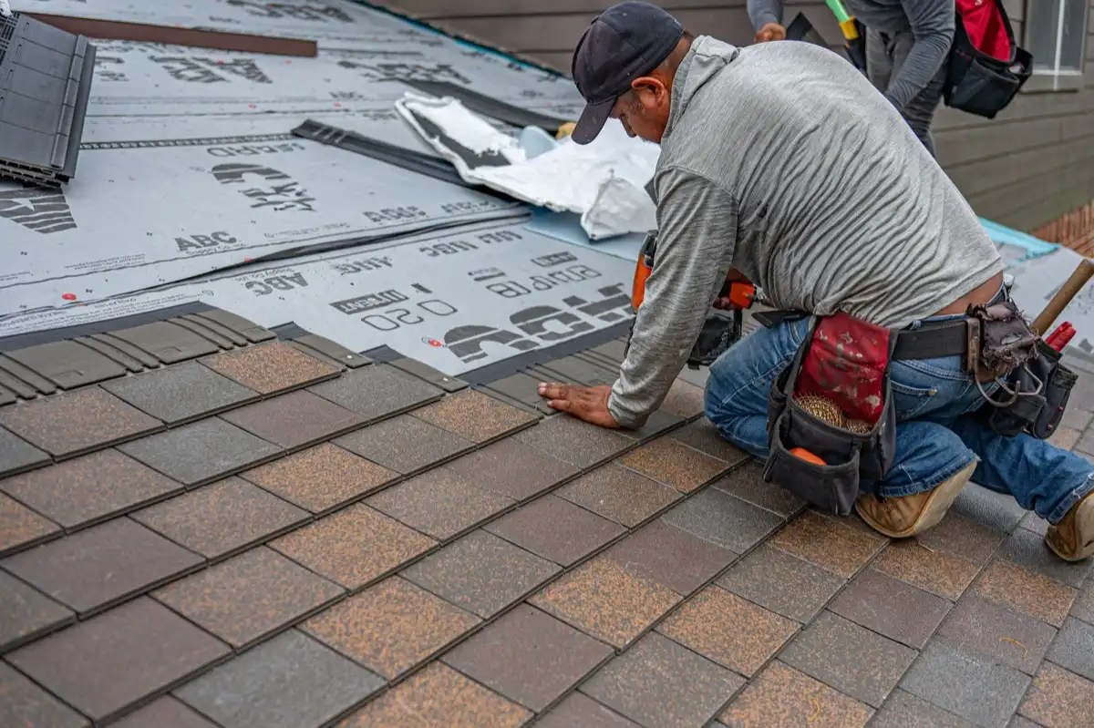 Roofing installer fastening shingles over new underlayment in Tempe, AZ